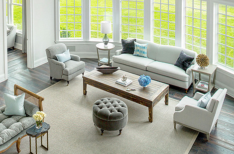 Custom modern styled tufted ottoman, custom Broome Sofa, and custom Bridgewater Chair with wooden castor legs.Interiors: Robyn Karp Design. Upholstery: Bespoke By Luigi Gentile