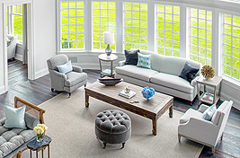 Custom modern styled tufted ottoman, custom Broome Sofa, and custom Bridgewater Chair with wooden castor legs.Interiors: Robyn Karp Design. Upholstery: Bespoke By Luigi Gentile